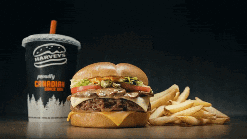 a hamburger and french fries sit next to a harvey 's cup