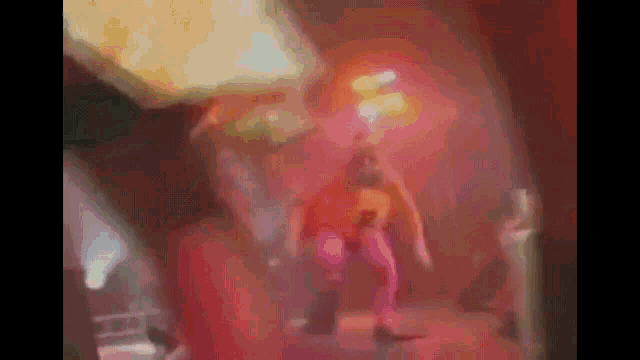 a blurry picture of a man in a pink outfit dancing on a stage