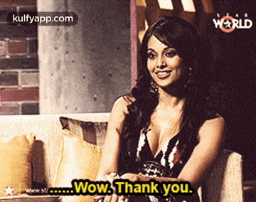 a woman is sitting on a couch and saying wow thank you .