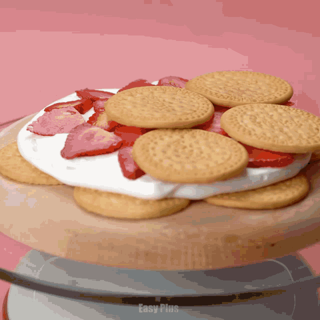 a cake with cookies strawberries and whipped cream on a glass plate that says easy plus on the bottom