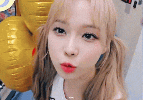 a close up of a woman 's face with balloons in the background .