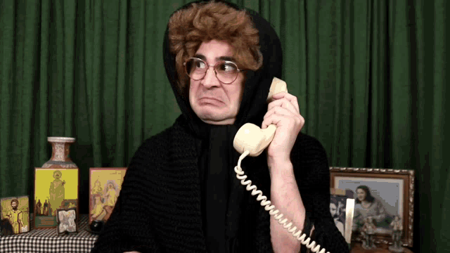 a man talking on a telephone with a picture of jesus in the background