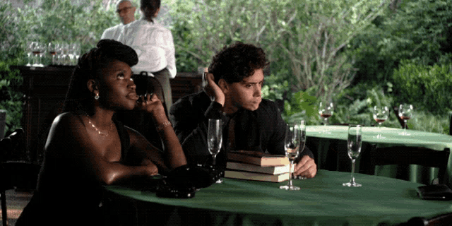 a man and a woman sit at a table with wine glasses