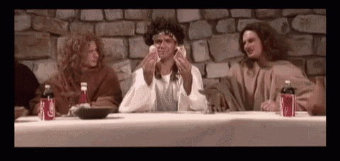 a group of people dressed as jesus are sitting at a table eating food and drinking soda .