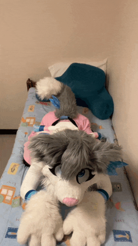 a stuffed animal is laying on a bed with a blue blanket that says bee on it