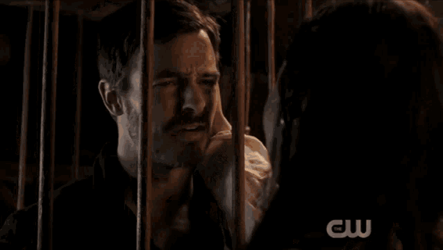 a man and a woman in a cage with a cw logo on the bottom