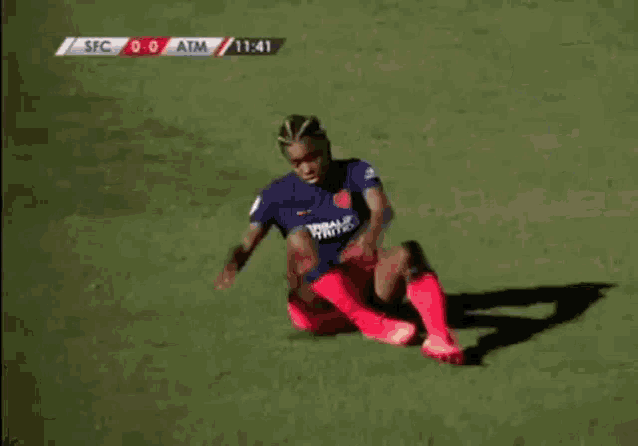 two women are playing soccer on a field and one of them is kneeling down on the ground .