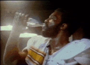 a man is drinking water from a bottle in a dark room .