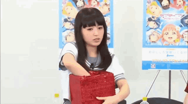a girl in a school uniform is holding a red bag in her hands .