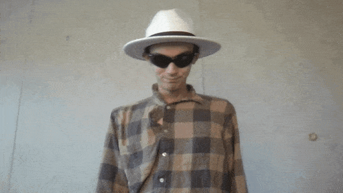 a man wearing a plaid shirt and a hat with sunglasses