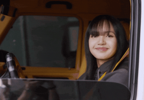 a woman with long black hair is sitting in a car and smiling