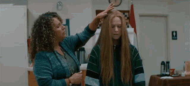 a woman is touching another woman 's hair in a room