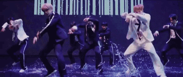 a group of men in suits are dancing on a stage in front of a barcode .