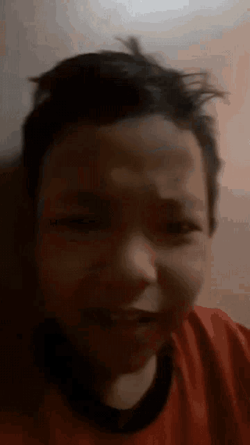 a young boy in a red shirt is making a sad face