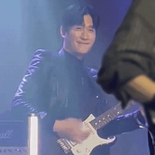 a man playing a guitar with a marshall amplifier behind him