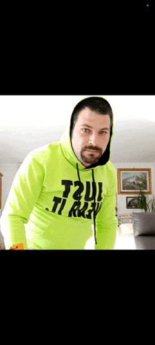 a man wearing a neon green hoodie that says t2ui ti raju