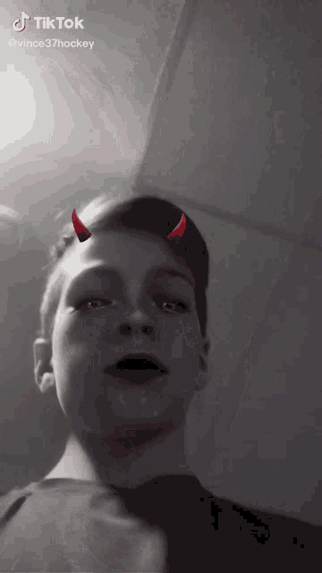 a young boy with devil horns on his face is a tik tok video