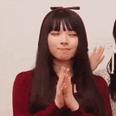 a woman with long hair and bangs is making a funny face with her hands together .