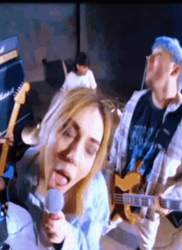 a woman sings into a microphone while a man plays a guitar
