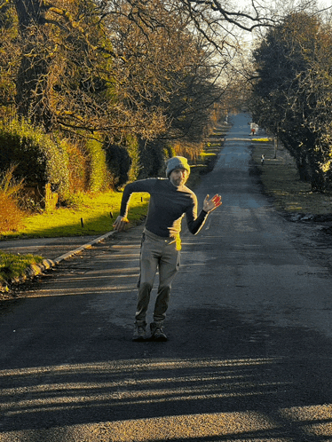 a person is walking down a road with trees on the side