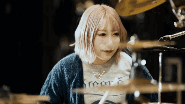 a girl with pink hair is playing drums and wearing a shirt that says ' roots ' on it