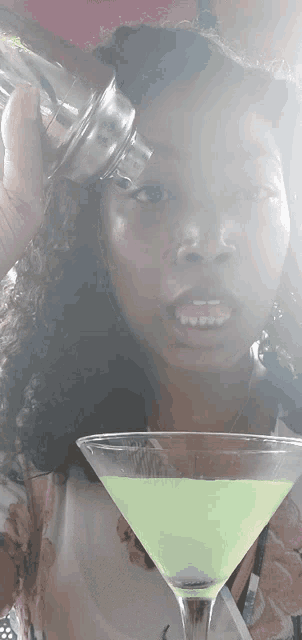 a woman is pouring a drink into a martini glass and making a funny face