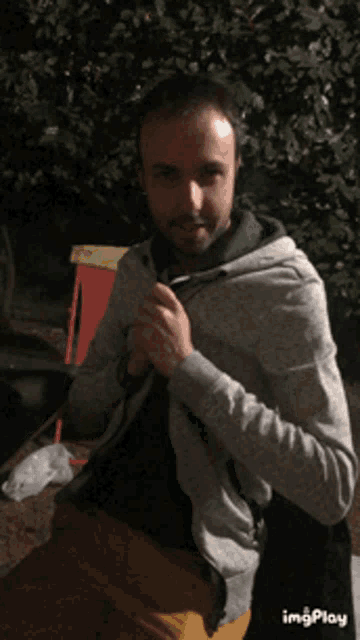 a man is wearing a grey hoodie and a black shirt