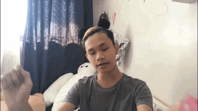a young man in a grey shirt is sitting in front of a white teddy bear