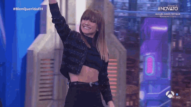 a woman in a crop top is dancing on a stage in front of a sign that says #novato