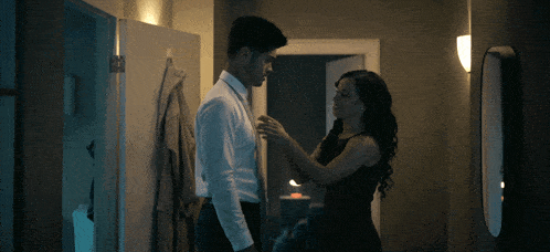 a woman in a black dress is helping a man with his tie