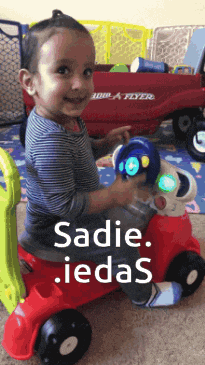 a little boy is sitting on a red toy car with the words sadie iedas written on the bottom