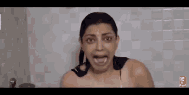 a woman is taking a shower in a bathroom with her head in the water .