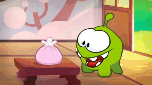a green cartoon character is standing next to a pink bag