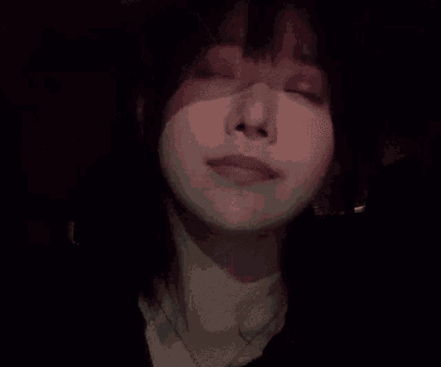 a close up of a woman 's face with her eyes closed in the dark