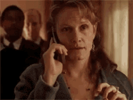 a woman is talking on a cell phone with a man behind her