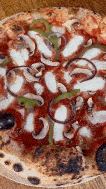 a pizza with mushrooms peppers and onions on a wooden table