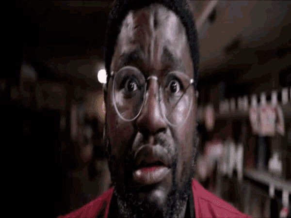 a man wearing glasses and a red jacket looks surprised