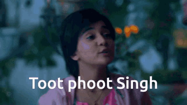 a girl in a pink shirt is standing in front of a sign that says toot phoot singh .