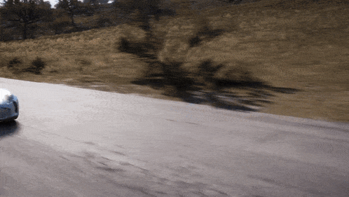 a car driving down a road with a shadow of a tree on the ground