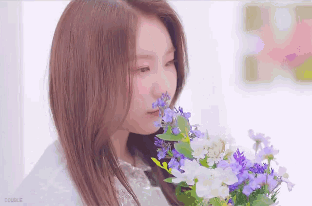 a woman smelling a bouquet of purple and white flowers with double written on the bottom right