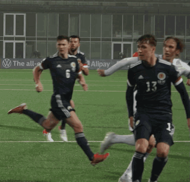 a group of soccer players are running on a field with an electric id 4 banner in the background
