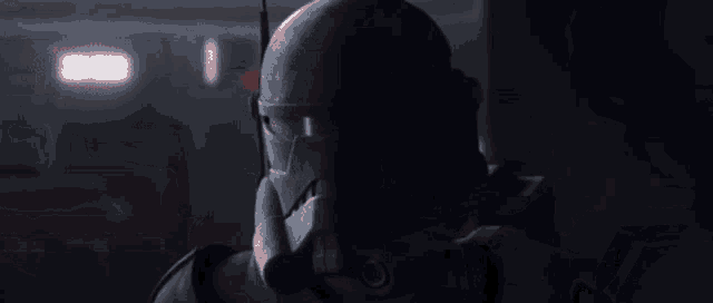 a close up of a person holding a gun in a dark room with a red light behind them .