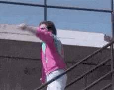 a man in a pink shirt is jumping off a staircase .