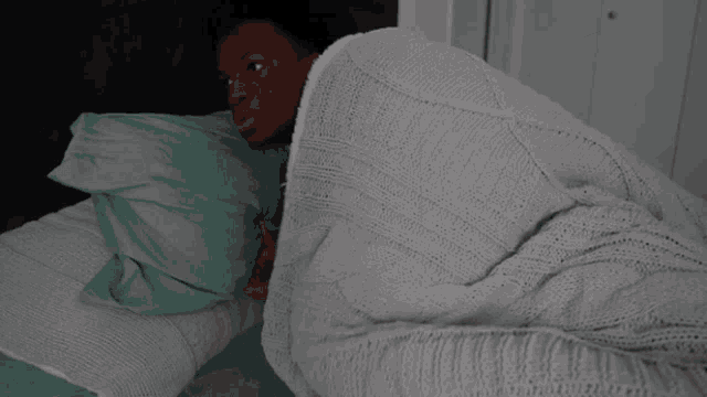 a person laying on a bed with a blanket on them
