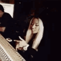 a woman with long blonde hair is sitting in front of a microphone in a dark room .