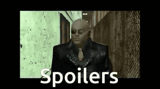 a bald man in a suit and tie is standing in a hallway with the words spoilers written on the bottom .