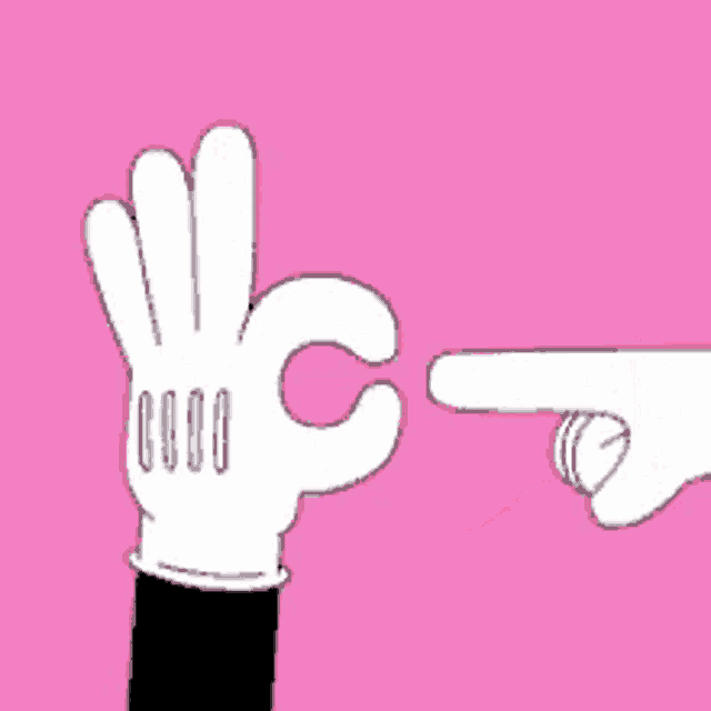 a person wearing a mickey mouse glove is pointing at another person 's hand with a pink heart in the background