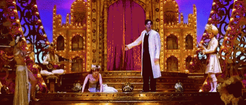 a man in a white coat is standing on a stage with a woman in a white dress