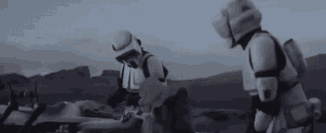 two storm trooper soldiers are standing next to each other on a desert planet .
