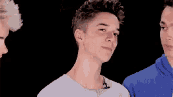 three young men are standing next to each other and one of them is wearing a blue hoodie